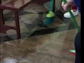 Fieis tirando água que inundou o piso da igreja