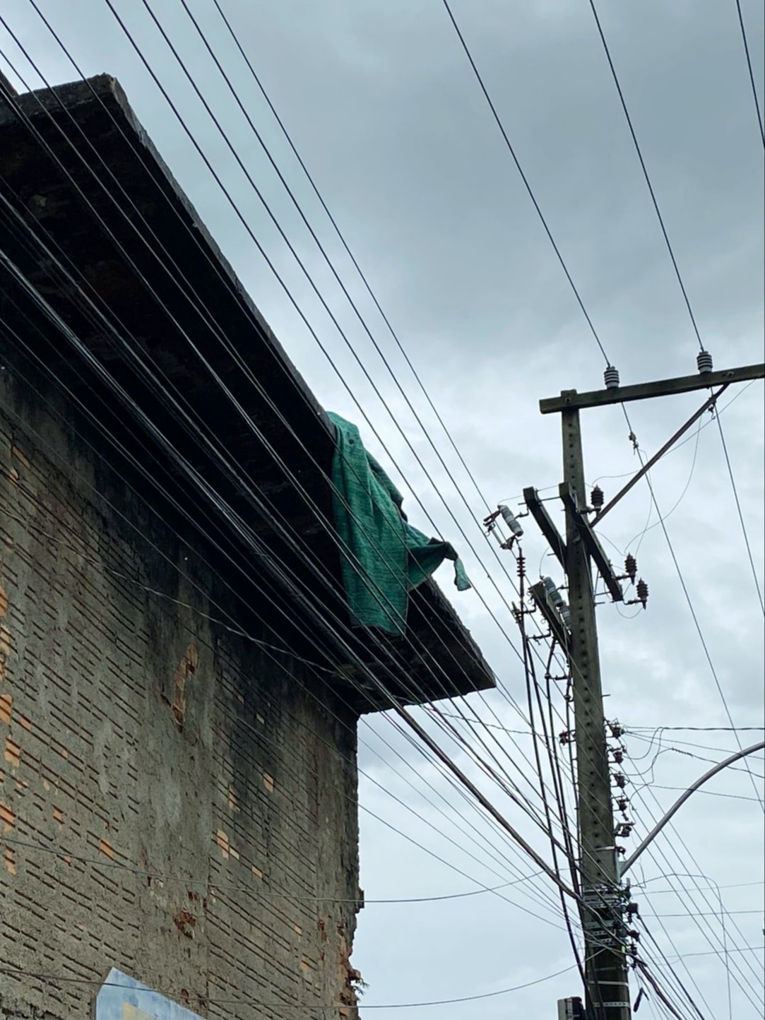 cobertor na beira de prédio próximo a fios
