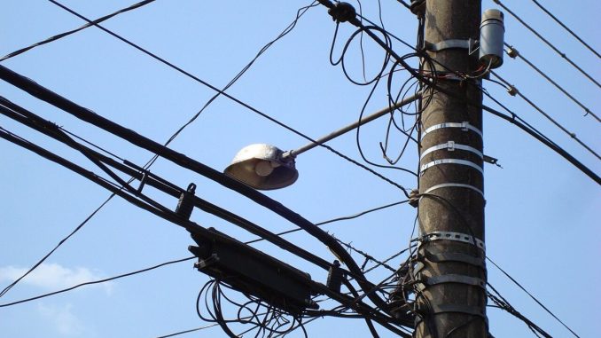Poste de concreto com fios da rede elétrica aérea e luminária de iluminação pública